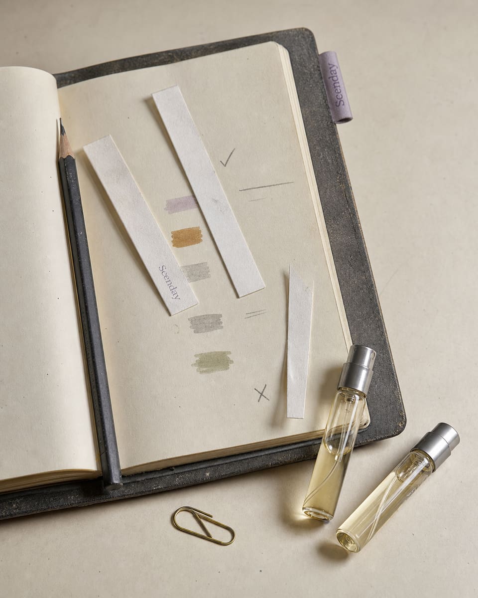 An open notebook of scent strips and colour swatches on the Scenday desk, beside two sample vials.